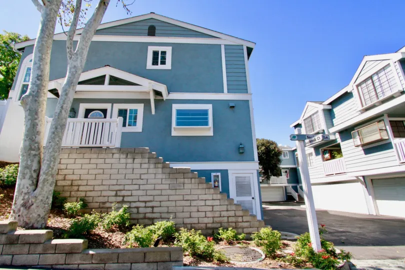 Garden Park Village apartments with a staircase and a tree on a sunny day.