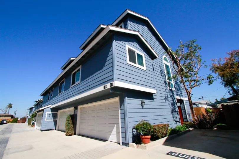 Harbor Pointe North blue apartment building with a garage and trees on a sunny day.