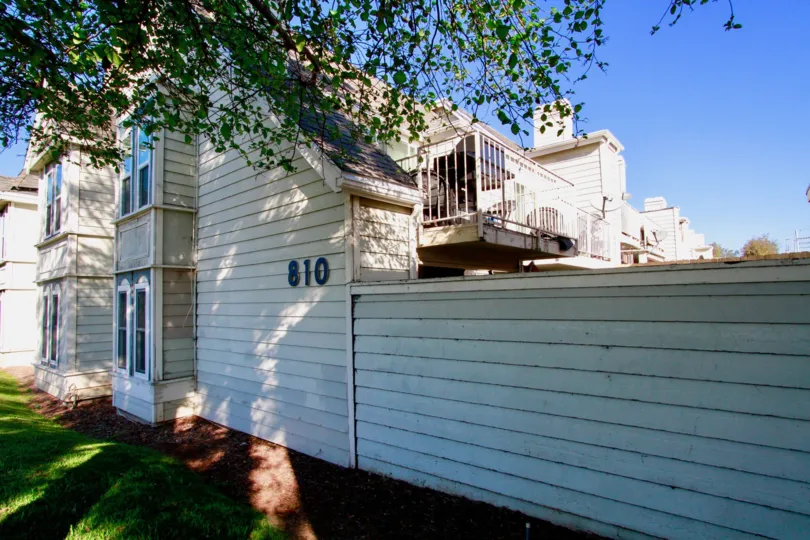 THE BUILDING WITH THE NUMBER EIGHT ONE TEN AT THE WALL OF THE BUILDING AND A TREE IN FRONT OF THE HOUSE AND A LONG WALL AT THE RIGHT SIDE OF THE APARTMEMENT