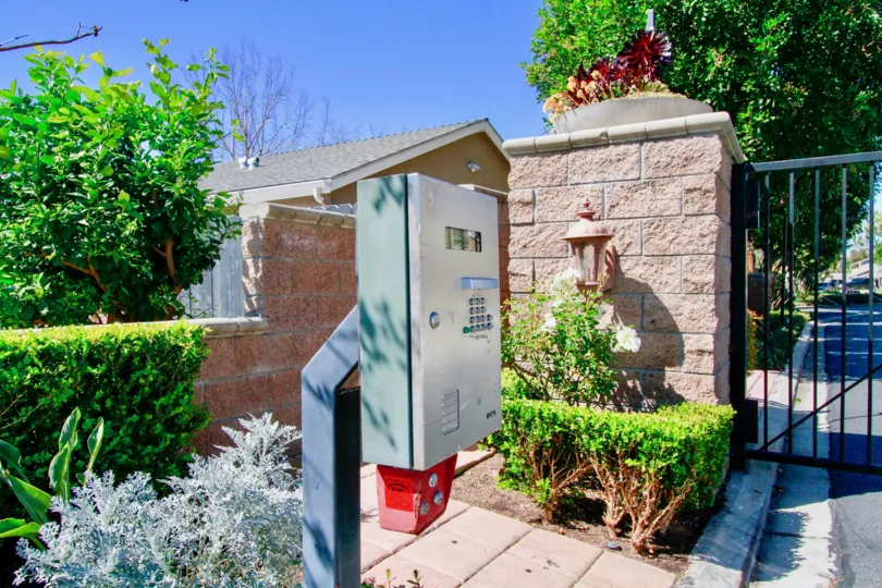 THE MAIN GATE WITH THE CALLING PHONE AND A BEAUTIFUL GARDEN ALSO AVAILABLE AT THE PLACE IN THE MORNING SUNSHINE TIME.
