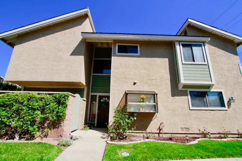 A large house in Costa Mesa CA with multiple plants growing on a sunny day.