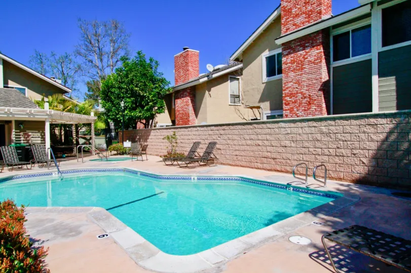 Laurel Point pool with a stone fence and deck chairs on a sunny day.