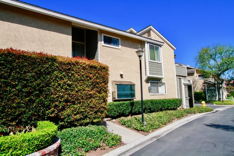 Laurel Point apartment building with bushes and street lamps on a sunny day.