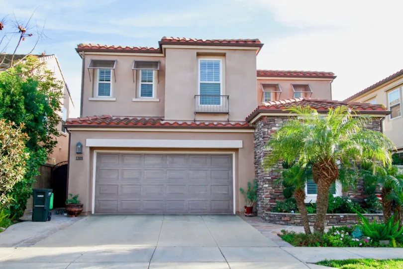 Laurels at Providence Ranch two story home with palm trees and a trash can.