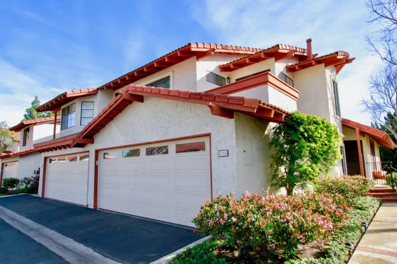 White with red accented multi-family two-story buildings with landscaping in the Longwood Greens community of Costa Mesa, CA