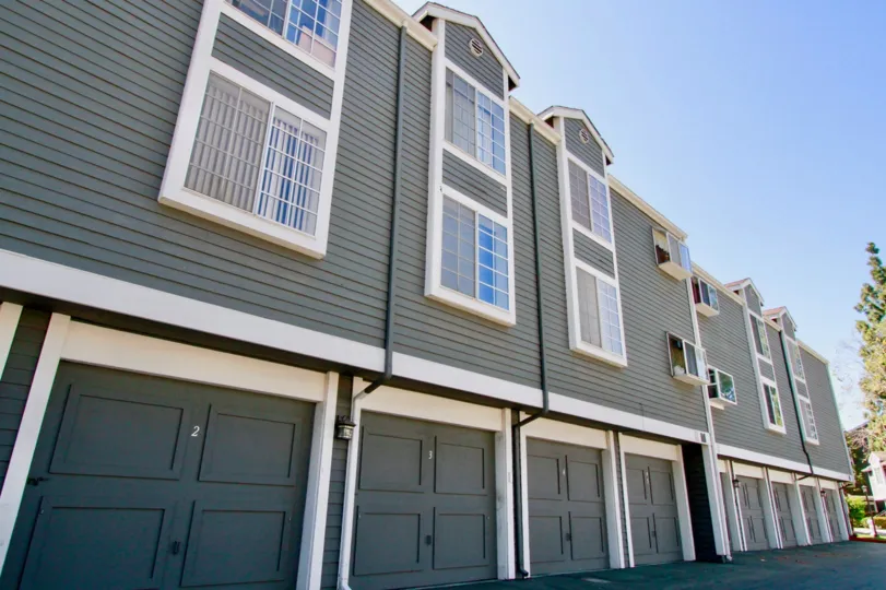 Newport Landing gray apartments with garages on a sunny day.