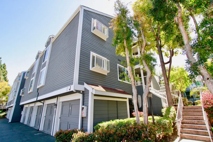Newport Landing apartments with a staircase and trees on a sunny day.