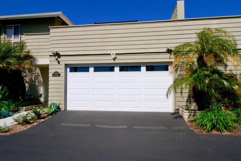 Newport Riviera home with a garage and trees on a sunny day.