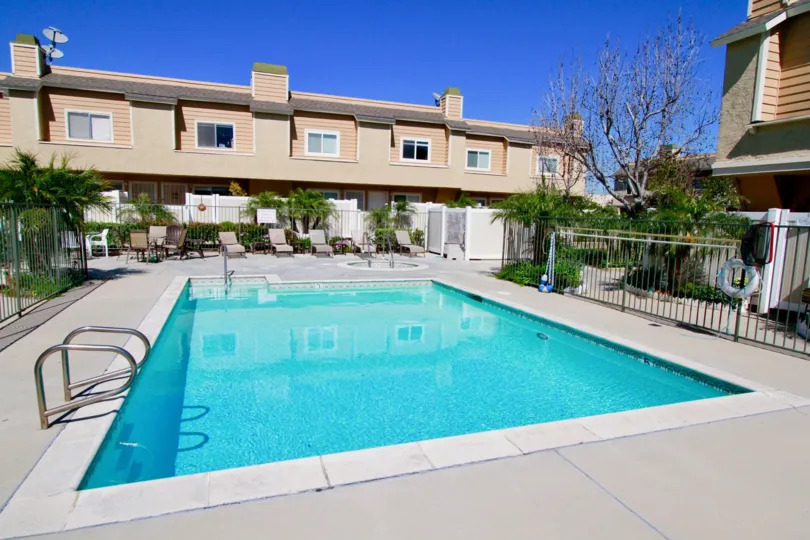 A large blue rectangle pool surrounded by a black iron fence at ocean Breeze Villas in Costa Mesa CA