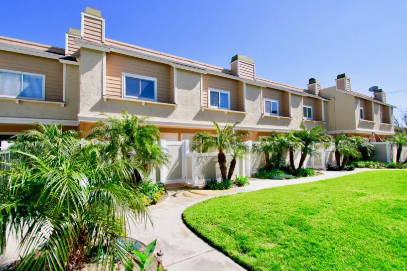 Ocean Breeze Villas apartments with fences and palm trees on a sunny day.
