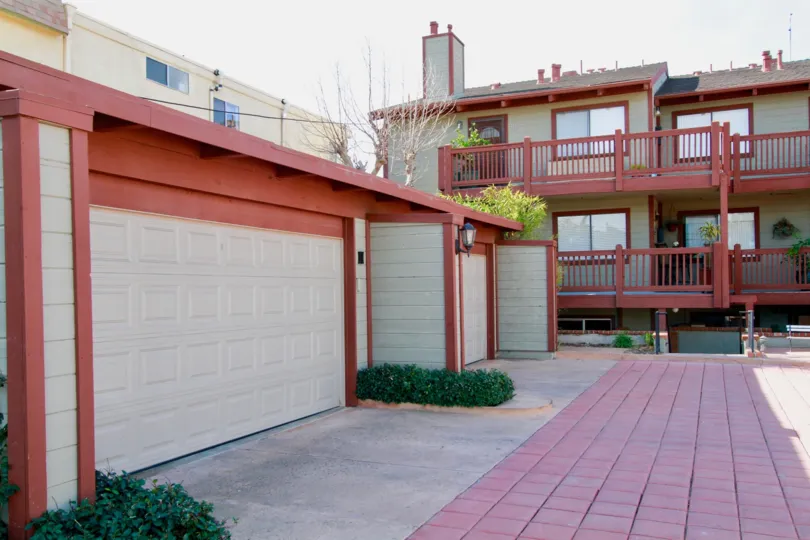 Apartment homes in a bright red and tan design, pictured are garages and 2 porches