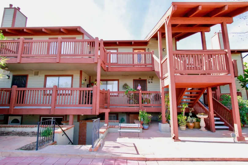 Pacific View apartment building with a staircase and potted plants on a cloudy day.