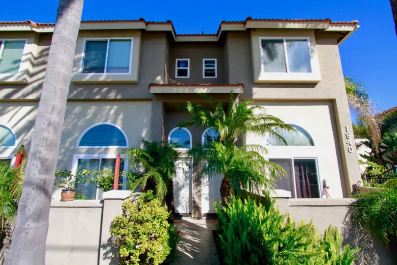 Palermo Townhomes two story apartment building with palm trees on a sunny day.