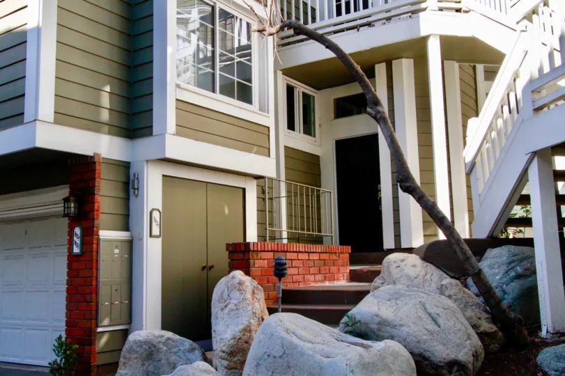 A BUILDING WITH STONES IN FRONT OF THE HOUSE AND UPSTAIRS STEPS ALSO AVAILABLE AND THE SKY ALSO LOOKING HOT SUNSHINE.