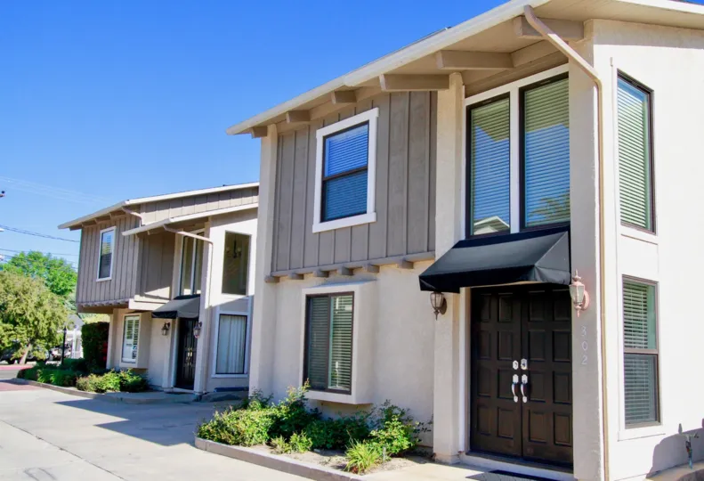 Peppertree Heights two story apartments with brown doors on a sunny day.