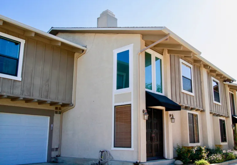Peppertree Heights apartment buidling with a brown door and a hose on a sunny day.