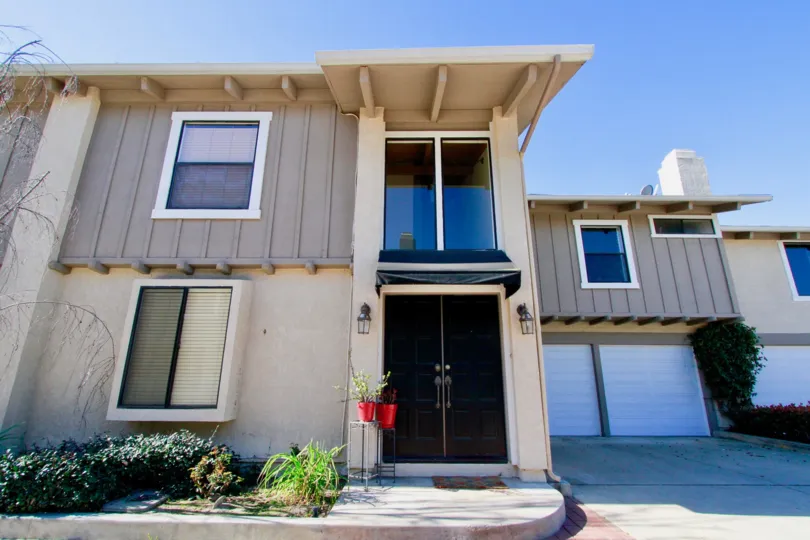 Peppertree Heights two story apartments with garages brown doors on a sunny day.