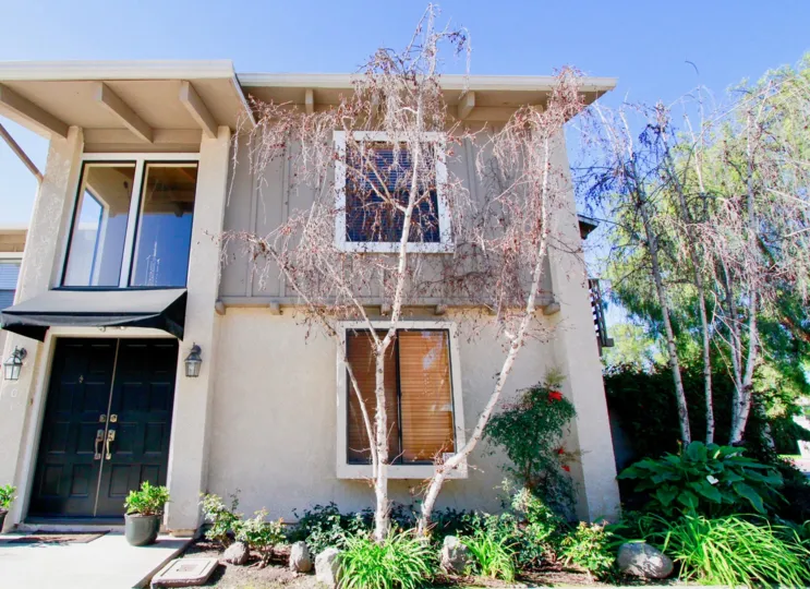 Peppertree Heights two story apartments with trees and brown doors on a sunny day.