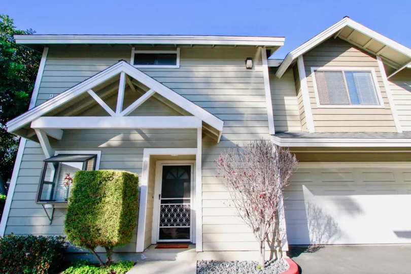 The home in the Quiet Bay Townhomes is look like a cottage house with trees and plants.