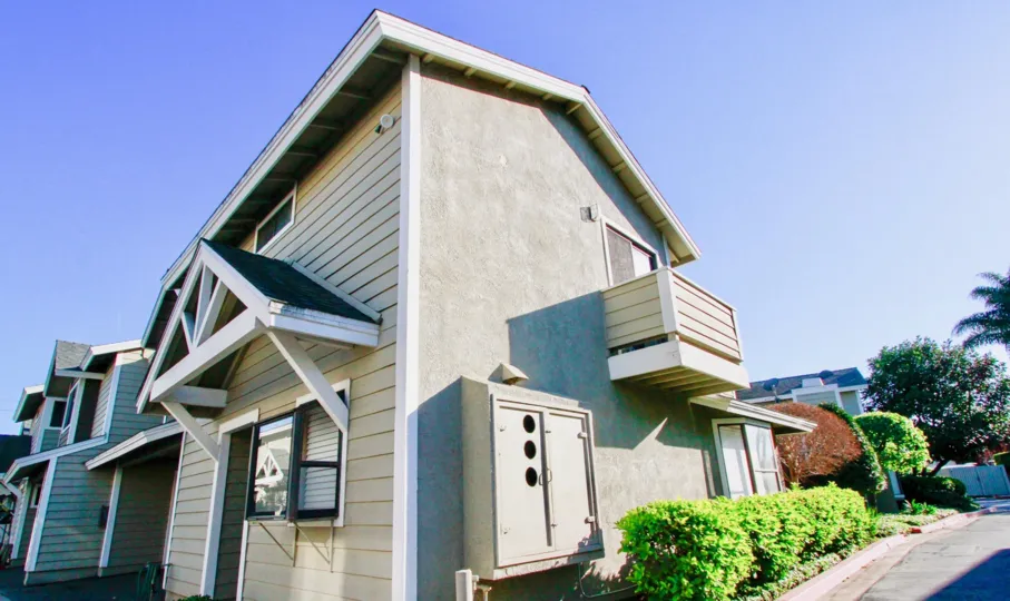 Quiet Bay Townhomes homes with bushes and balconies on a sunny day.