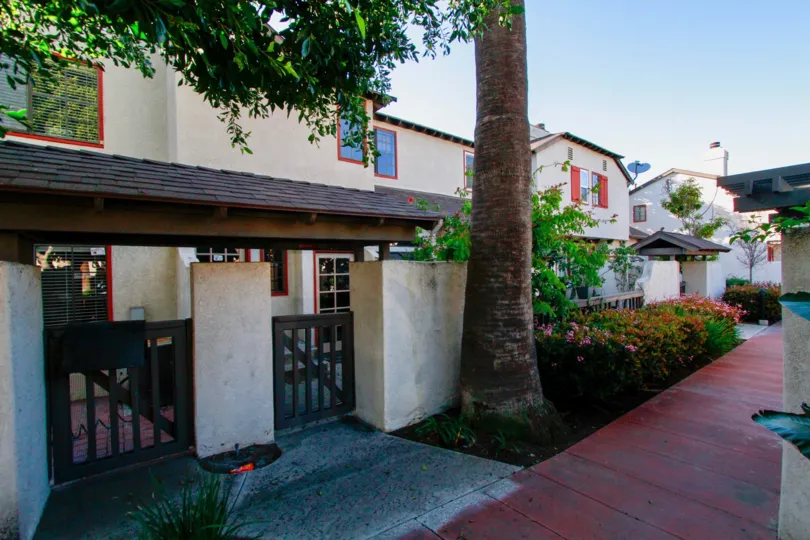 Row of white stucco two-story units with gated outdoor area and lush landscaping at San Michel in Costa Mesa, CA