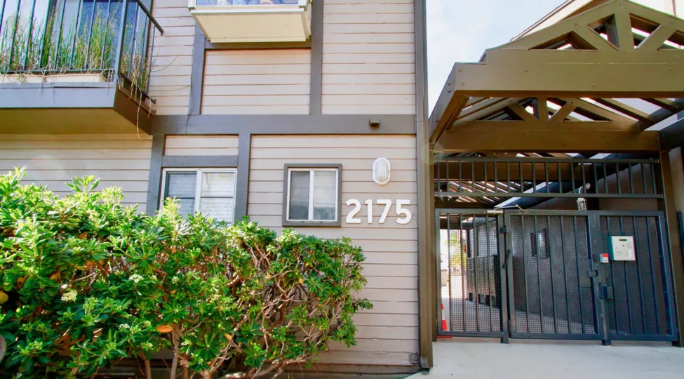 Sea Ridge community gate and street number with bushes on a sunny day.