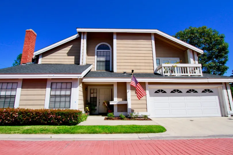 Spinnaker Cove home with a flag and garage on a sunny day.