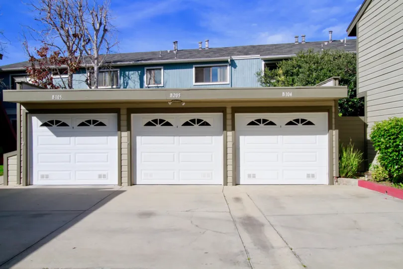 A three car garage with house or apartment complex in the background