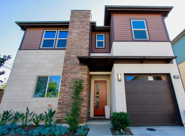 A condo in The Edge with a garage and red door on a sunny day.