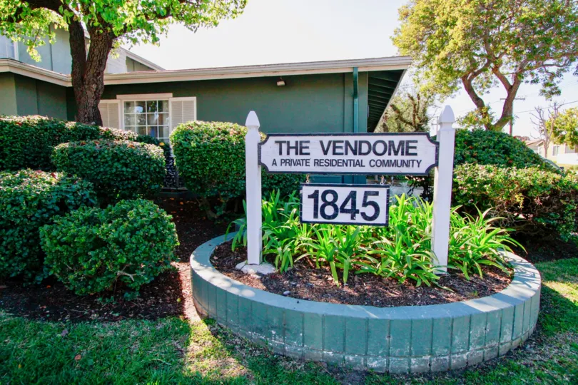 The Vendome sign with plants and trees on a sunny day.
