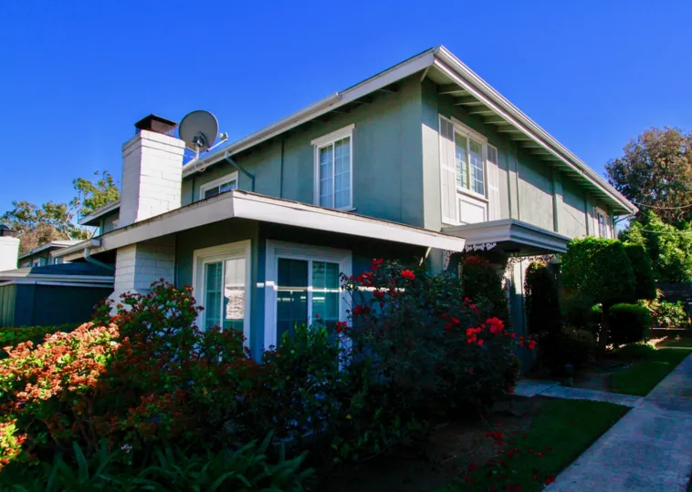 The Vendome home with bushes and trees on a sunny day.