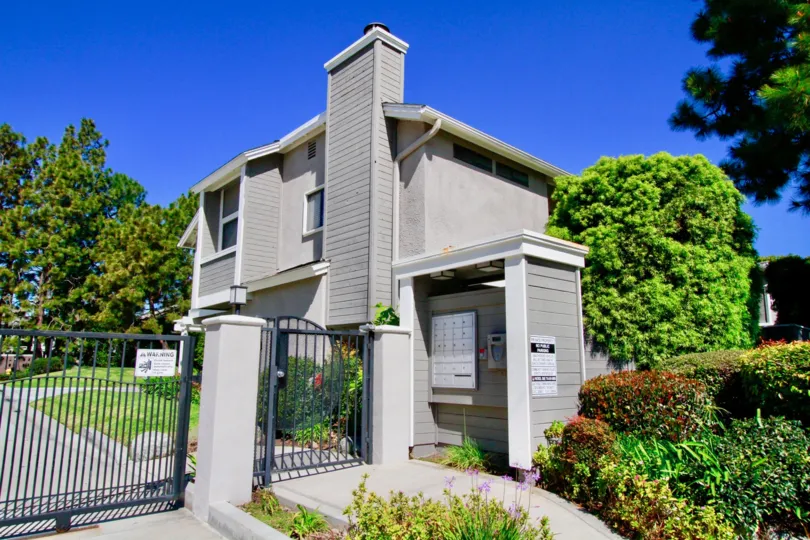 A gated fence with a grey house and well kept lawn behind it