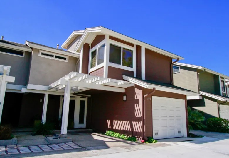 Two story brown condo with attached garage with white door at The Village At Admiral Way in Costa Mesa CA