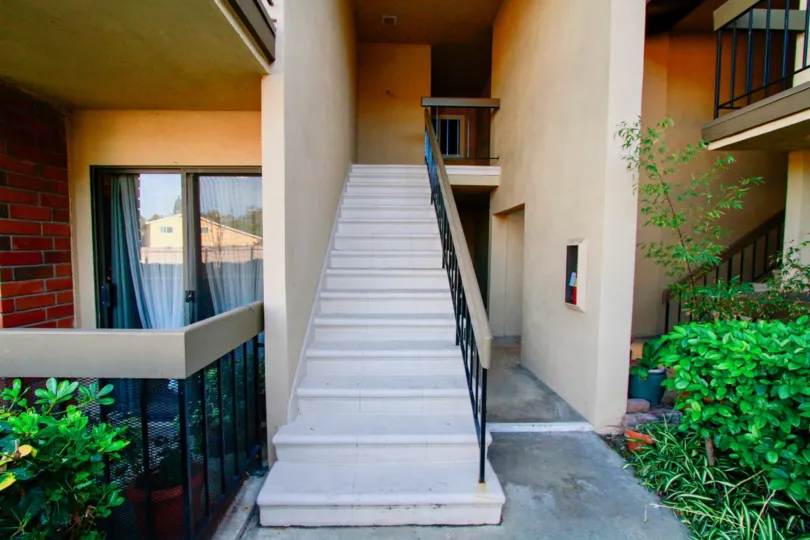 THE STEPS IS USED TO GO TO THE HOUSE UPSTAIRS AND WINDOWS WITH CLOTHES ARE AT THE GROUND FLOOR AND SOME PLANTS ALSO AT THE ENTRANCE OF THE HOUSE AT THE EARLY MORNING TIME