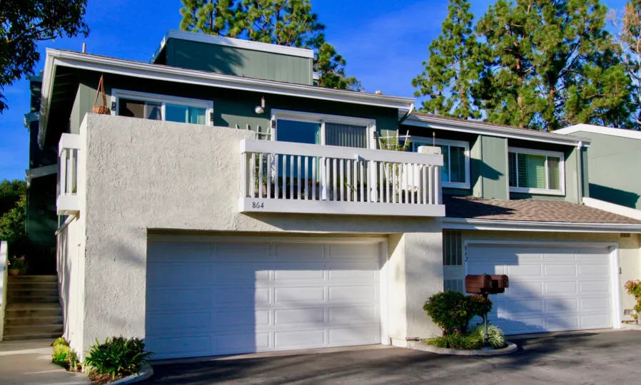 Village Creek apartments with a balcony and a garage on a sunny day.