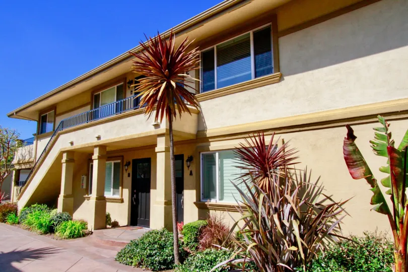 A beautiful home in the Vista Springs home with garden and bright looking front door with lots of trees and plants in that garden.