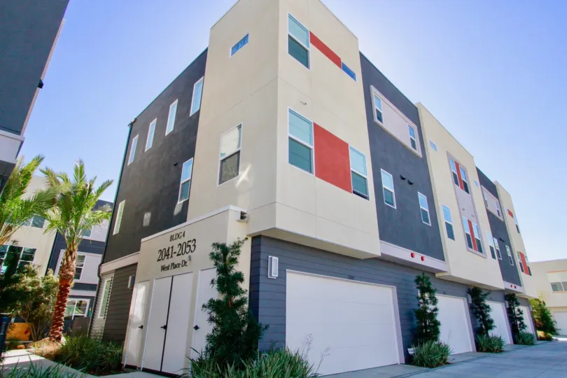 The big apartmants with glass windows in the West Place with palm trees and shrubs near the road side.