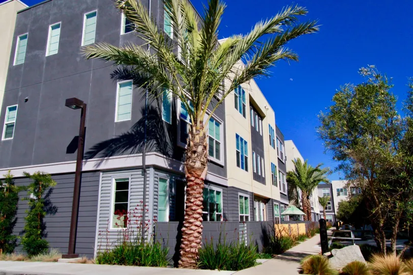THE BUILDING LOOKS LIKE APARTMENTS AND IT REPRESENT CRAY COLOR AND SOME TREES ALSO AVAILABLE NEAR TO THE HOUSE AND A LAMP ALSO THERE.