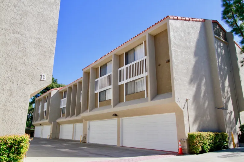 A big building in the Wilson Park Condos with big doors, ornamental flowring plants near the foot path.