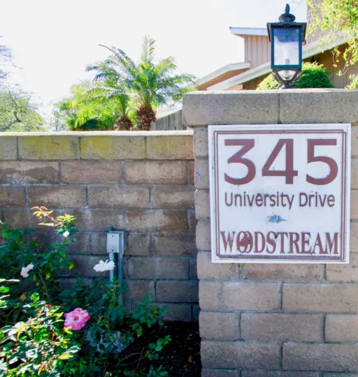 Sign for Woodstream Condos with palm trees on a sunny day.