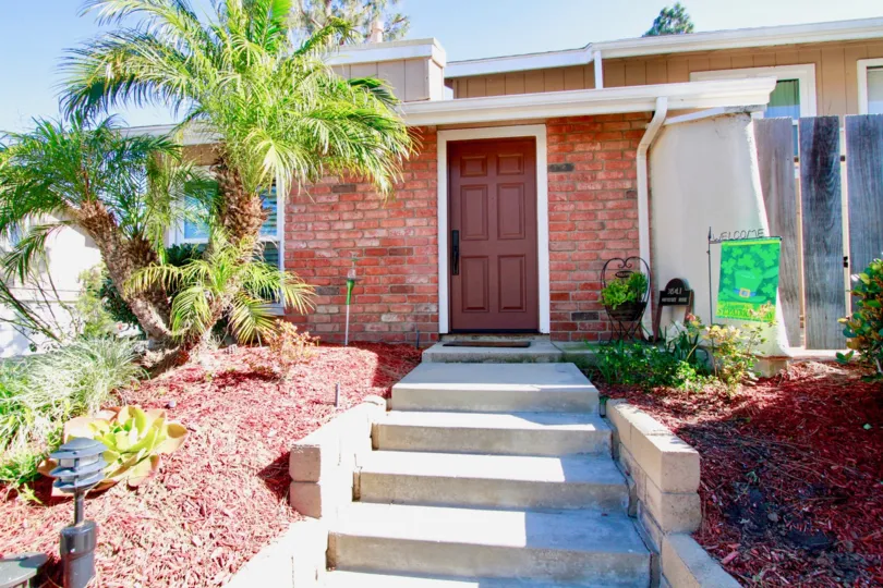 Sidewalk to a Woodstream Condos door with a palm trees on a sunny day.