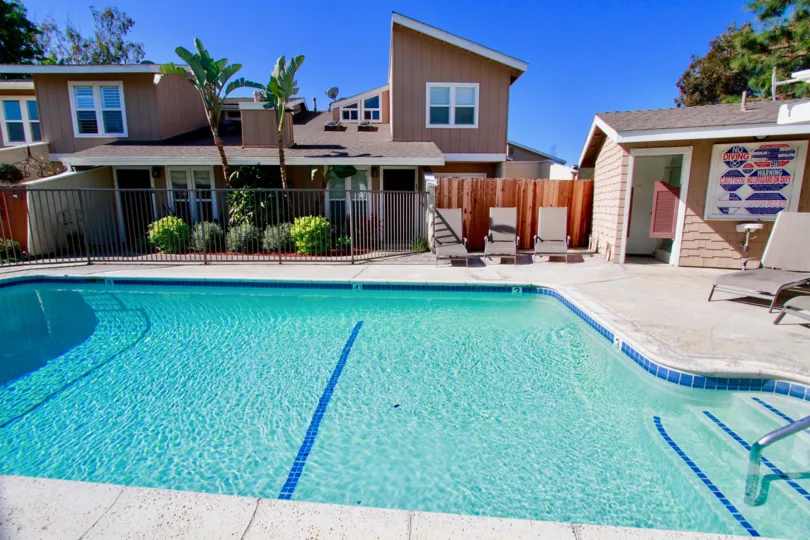 A Sunny Day in the Woodstream Condos swimming pool with some palm trees and deck chairs.