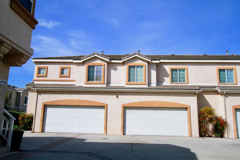 A HOUSE WITH TWO BIG SIZE DOOR LOOKS LIKE PARKING AND THE WINDOWS ALSO CLOSED AND A PLANT NEAR TO THERE AT THE MORNING SUN SHINE TIME
