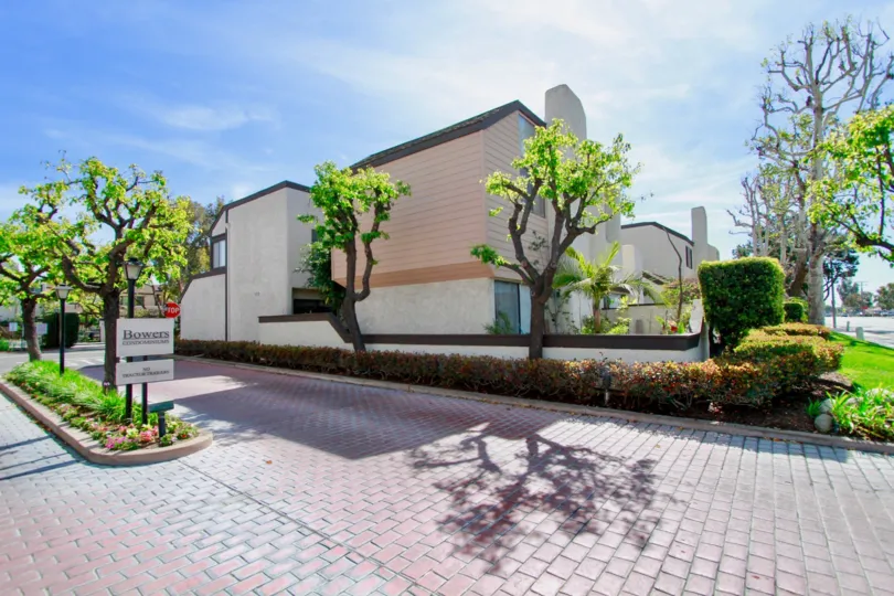 A BUILDING WITH THE ENTRANCE PATH AND LOOKS LIKE AN OFFICE PLACE AND SOME TREES AND PLANTS ALSO AVAILABLE AND IT LOOKS LIKE A GARDEN