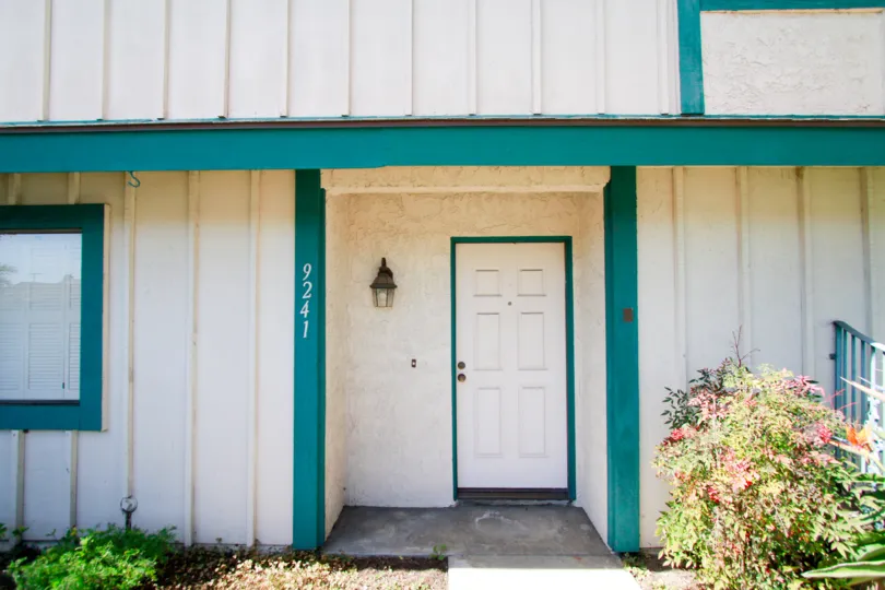 A look at the front door of a teal and white townhouse.