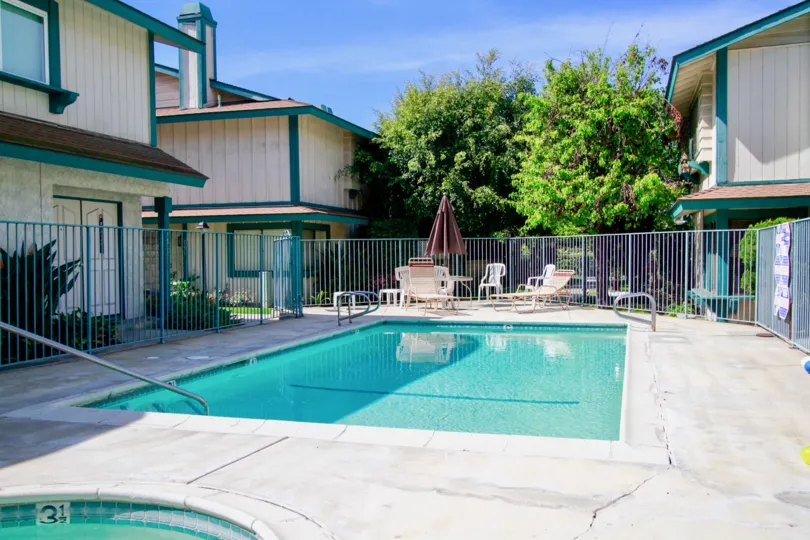 A SWIMMING POOL AND A SMALL POOL FOR KIDS ALSO NEAR AND THE APARTMENT BUILDINGS ALSO SURROUNDING THERE AT THE MORNING SUNSHINE TIME