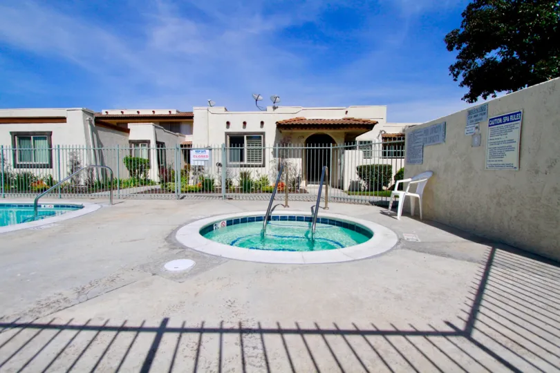 TWO SWIMMING POOL AT THE OUTSIDE AND THE ENTRANCE GATE WITH SMALL HOUSES AT THE MORNING TREES AND PLANTS AT THE SUNSHINE TIME