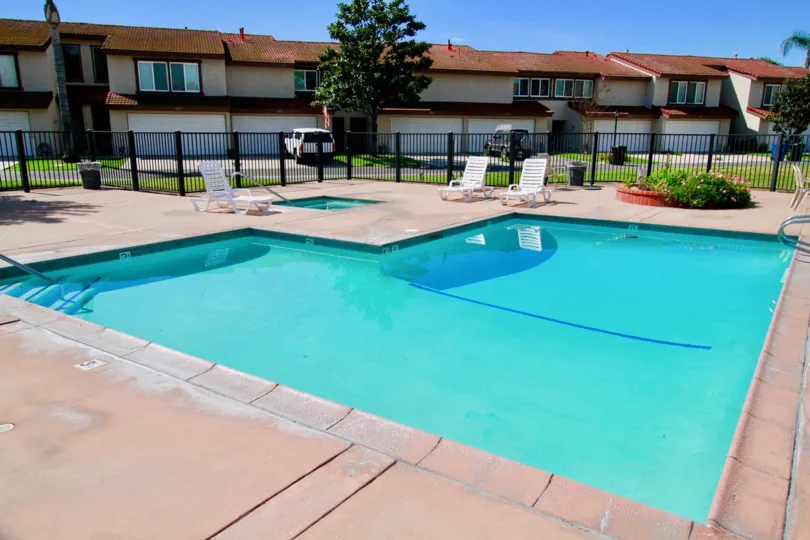 A SWIMMING POOL THAT LOCATED AT THE FRONT OF A PARALLEL BUILDINGS AND SITTING CHAIRS ALSO THERE