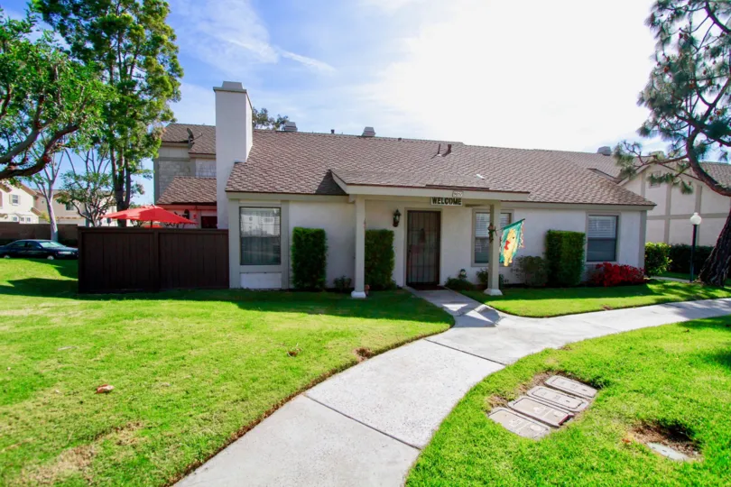 A sunny day at the front door of a Influential Townhomes' house with a well-cared grass front yard