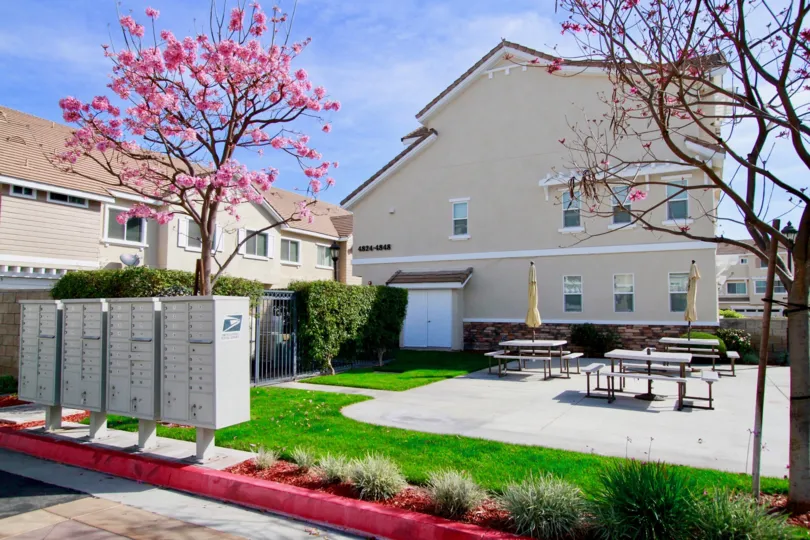 concrete patio with three picnic tables adjacent to community mailboxes and family home like building